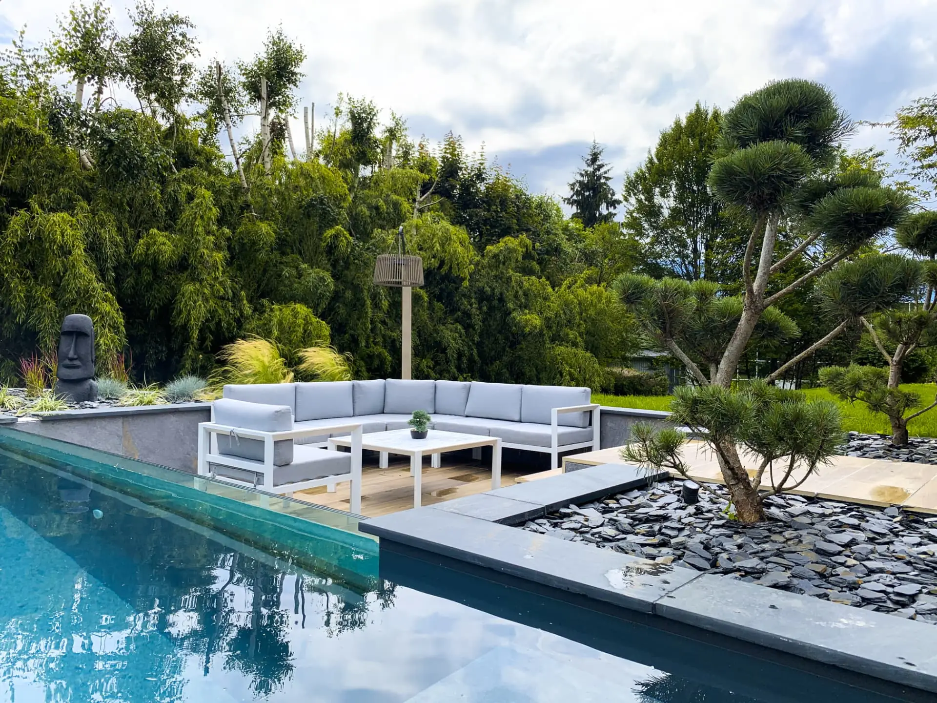 Salon extérieur au bord de la piscine, arbre taillé en nuage et paillage d'ardoise – Bonneville