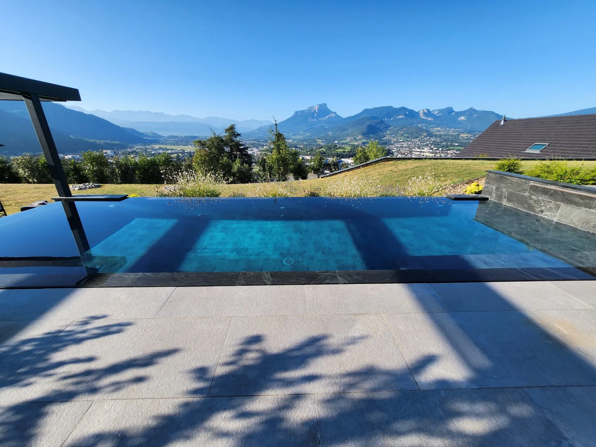 Piscine à débordement et dallage clair face aux montagnes – Saint-Alban-Leysse