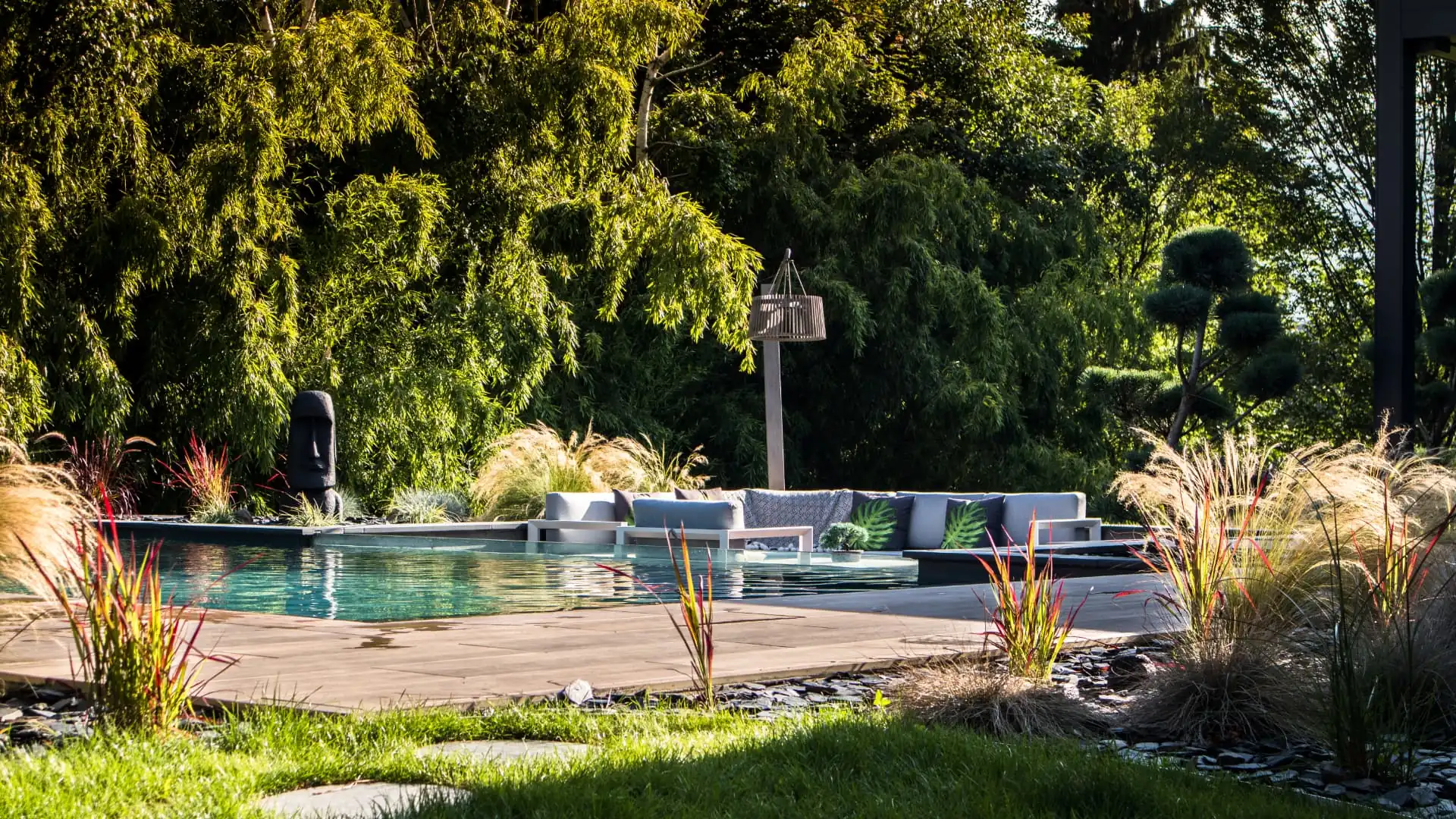 Piscine et terrasse en bois bordées de graminées et de pelouse – Bonneville