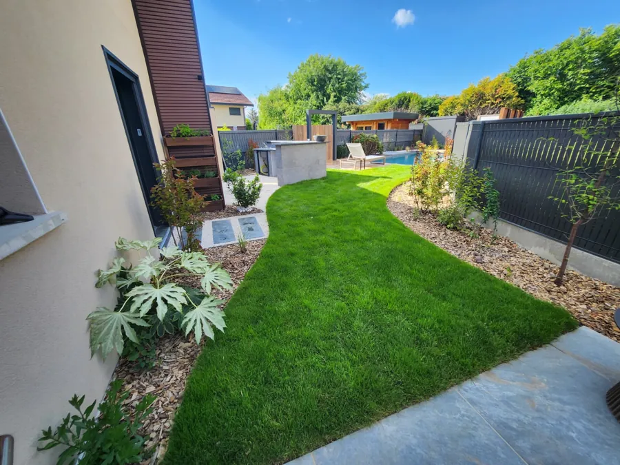Pelouse longeant la maison, massifs plantés et piscine en fond de jardin – Saint-Julien-en-Genevois