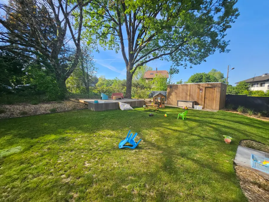 Grande pelouse ombragée par un arbre, cabane et abri en bois en fond de jardin – Seynod